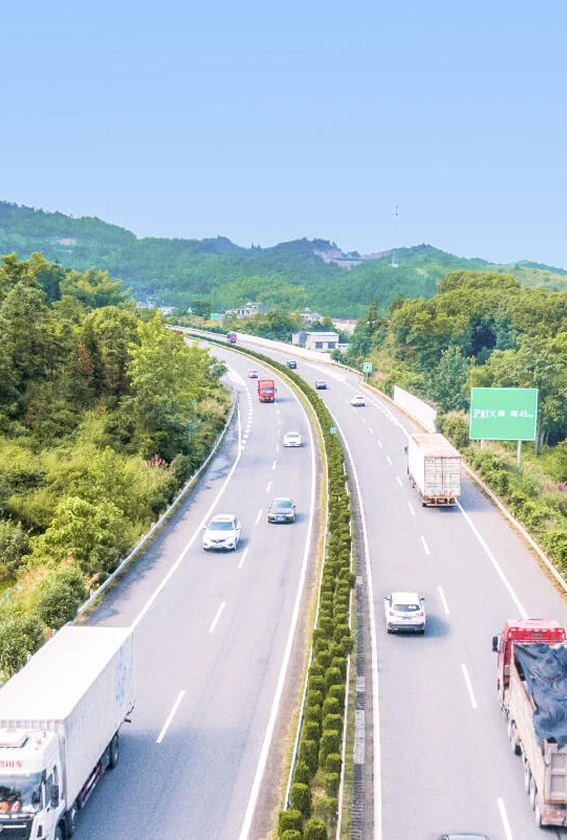 High-angle view of the Tomei Expressway in Japan, featuring traffic and a green directional sign against a backdrop of forested mountains