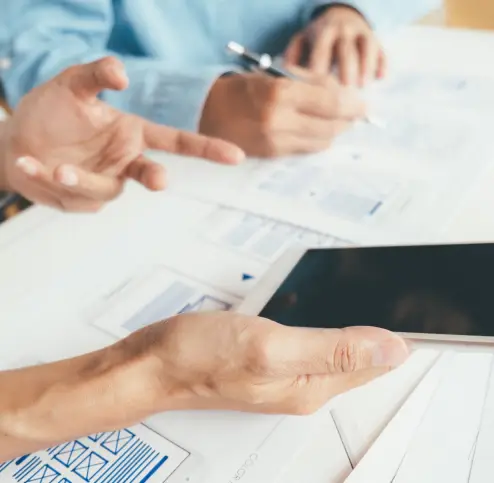 Close-up of two people’s hands writing while having a discussion.