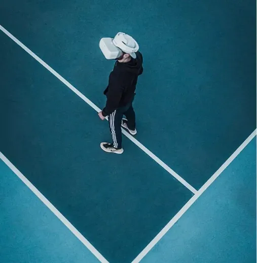 Aerial view of a person wearing a white VR headset, standing on a teal blue sports court with sharp white lines0